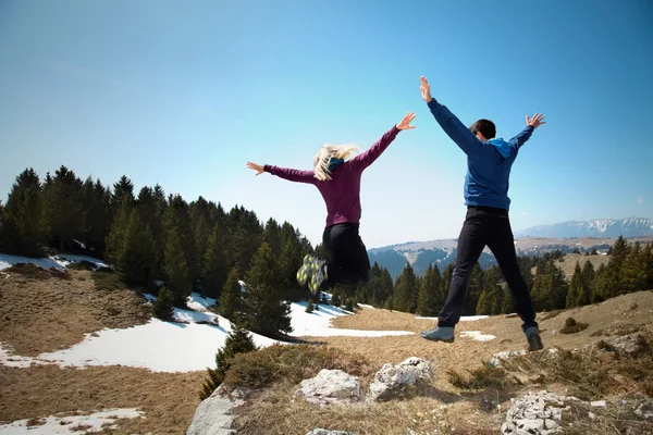 Excursionistas felices saltando en la cima de la montaña — Foto de Stock