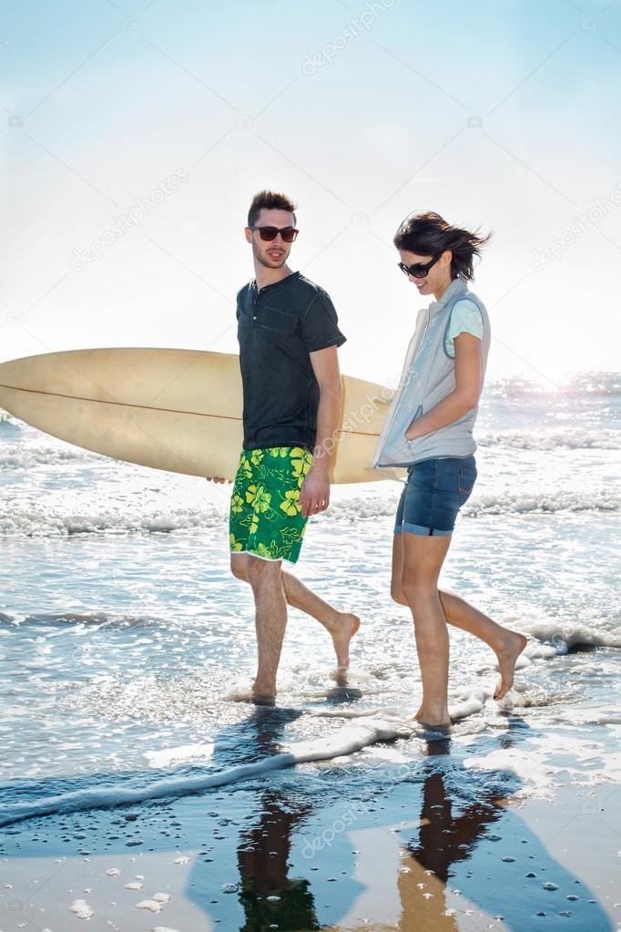 Couple of surfers running on the seashore