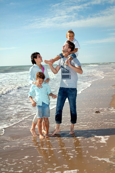 Happy Small Family Having a Vacation at the Beach During Summer