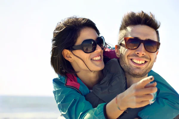 Mladá žena ukazuje její muž, výhled na moře, šťastný pár se baví na moři — Stock fotografie