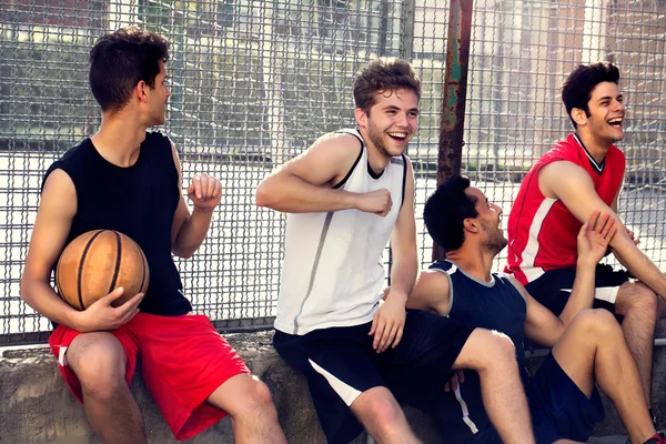 Jugadores de baloncesto toman un descanso sentado en una pared baja — Foto de Stock