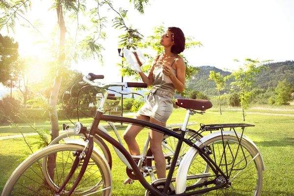 attractive woman on a bicycle resting under a tree