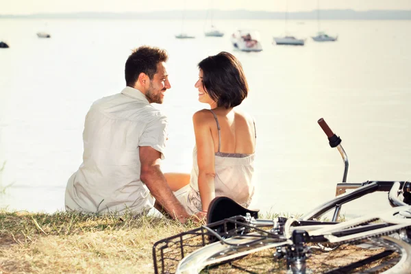 Coppia con bicicletta flirtare di fronte al lago — Foto Stock