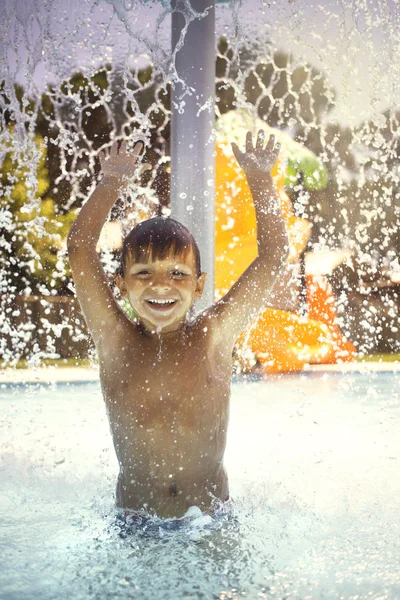 プールの水の噴水で遊んで幸せな少年 — ストック写真