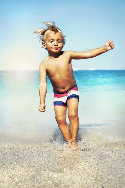 Funny boy jumping on the water at the sea — Stock Photo, Image