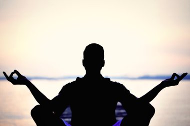 Adam arka ışık Yoga denizin önünde yapma