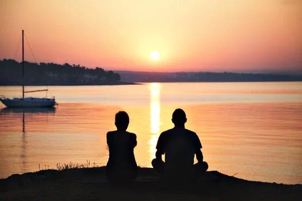 Couple rétroéclairé admirant le lever du soleil sur la mer — Photo