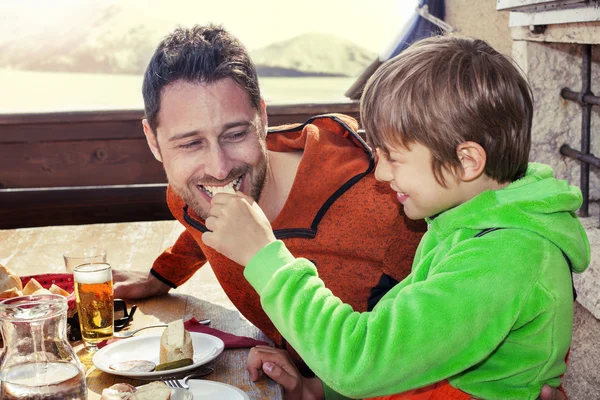 Father and son having lunch in a chalet in the mountain — Stock Photo, Image