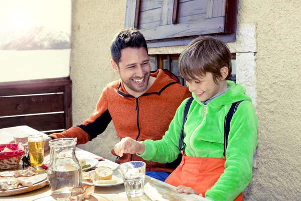 Father and son having lunch in a chalet in the mountain — Stock Photo, Image