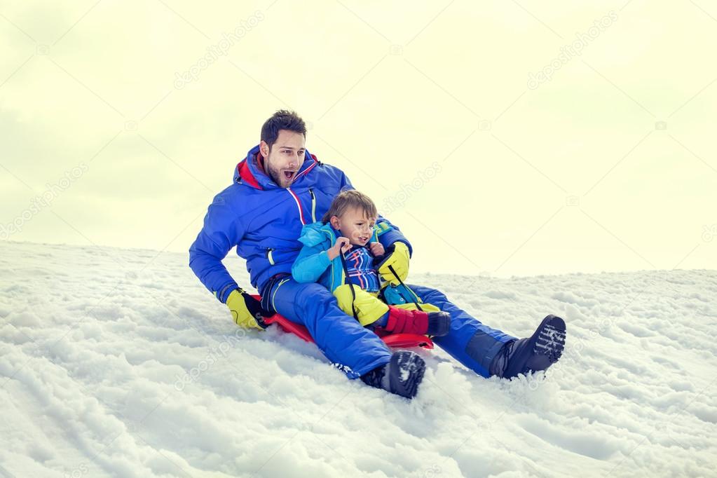 little boy and his father sledding very fast