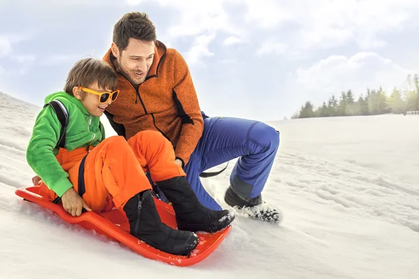 Father push the son in the bob over the snow — Stock Photo, Image