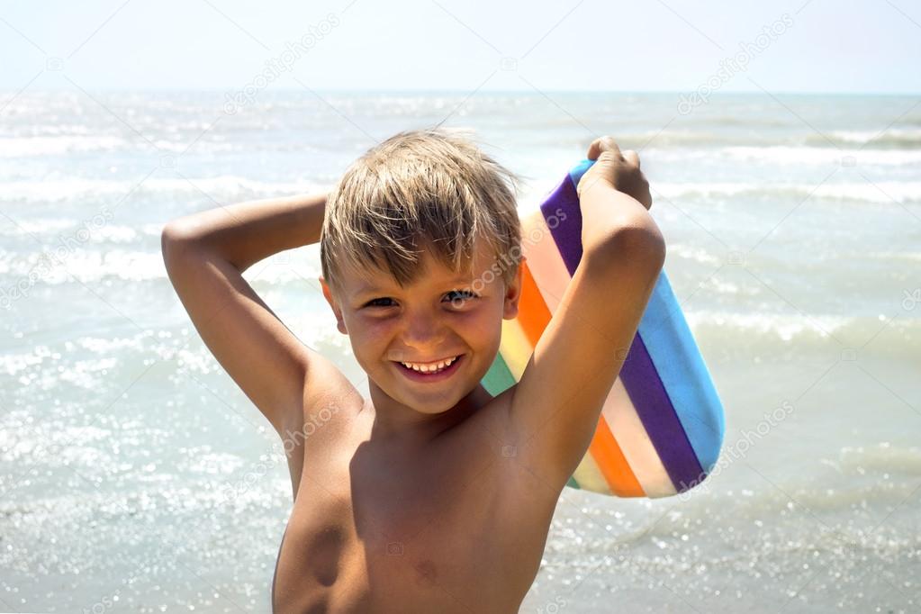 funny boy joking with kickboard on seashore
