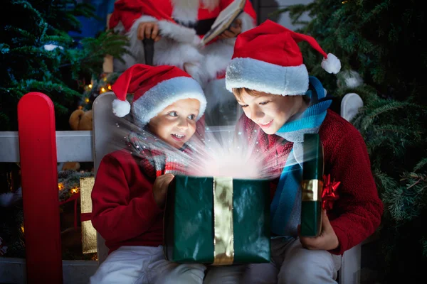 Duas crianças abrindo presente de Natal com raios de luz — Fotografia de Stock