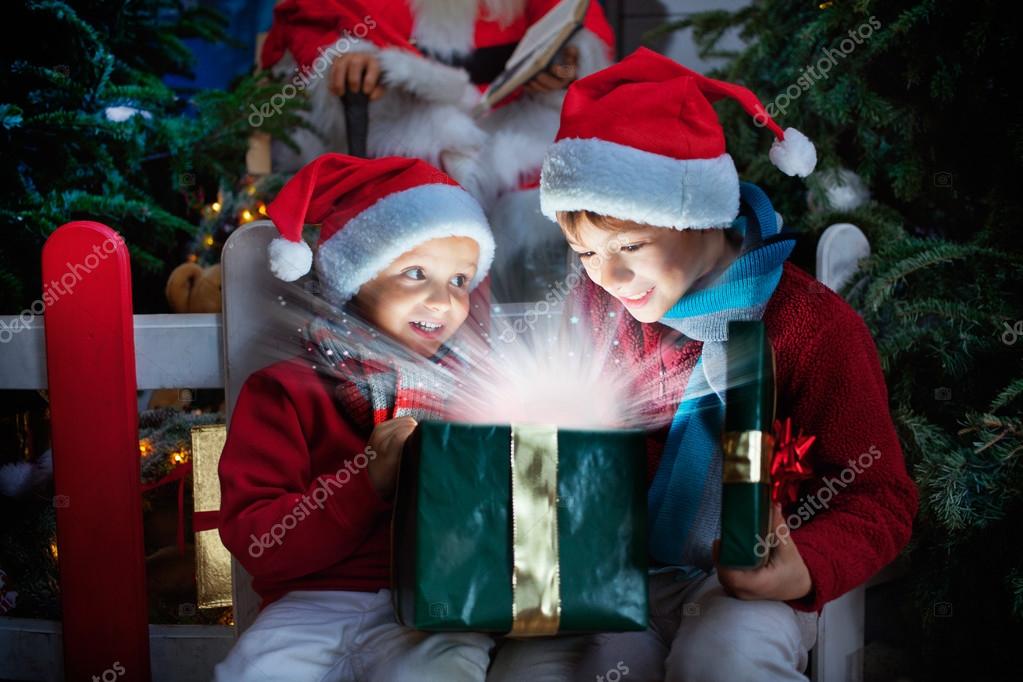 Two children opening Christmas gift with rays of light — Stock Photo © Cristina Conti 90940690