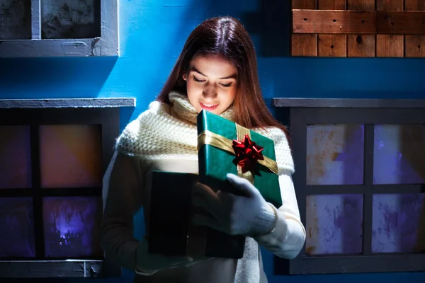 Młoda kobieta otwiera jej prezent Boże Narodzenie w magiczne i kolorowy — Zdjęcie stockowe