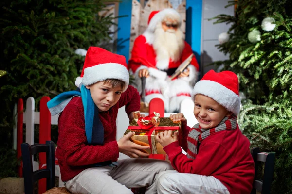 Due piccole clausole di Babbo Natale contendenti un regalo — Foto Stock