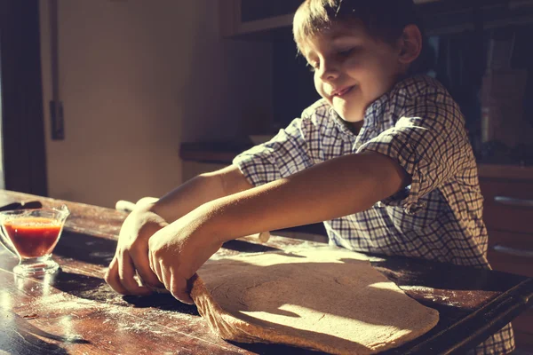 Зайнятий хлопчик намагається підняти тісто для піци — стокове фото