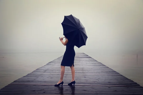 Vrouw met zwarte paraplu op zoek oneindigheid in een surrealistische place — Stockfoto