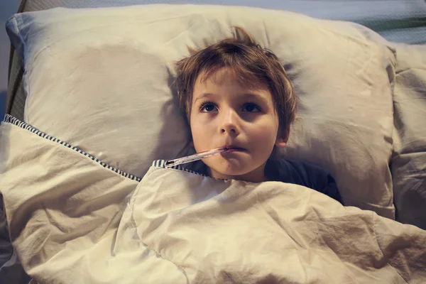 Kind krank im Bett mit Fieber und Thermometer — Stockfoto