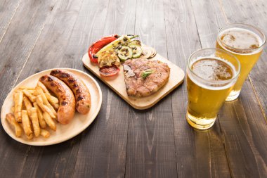 Salata ve bira ve kızarmış patates, w üzerinde sosis ızgara biftek