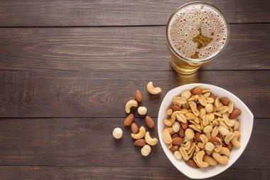 Bira ve badem, macadamia, fıstık, kaju fındık w üzerinde bardak