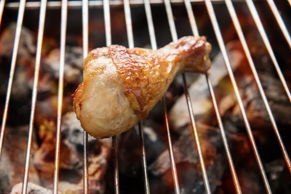 Grilled chicken drumstick over flames on a barbecue — Stock Photo, Image