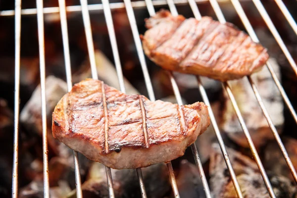 Grilled pork steaks over flames on the grill — Stock Photo, Image
