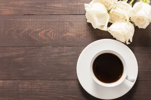 Een kopje koffie met witte rozen op de houten achtergrond — Stockfoto