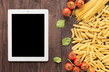Karışık kurutulmuş makarna seçimi ve tablet ahşap arka plan üzerinde