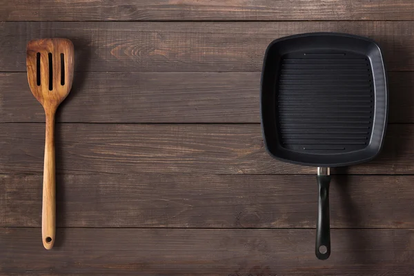 Чавунна сковорода та шпатель на дерев'яному фоні . — стокове фото