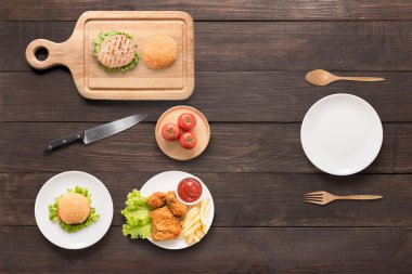 Kavram yeme hamburger, kızarmış tavuk, patates kızartması ve domates üzerinde