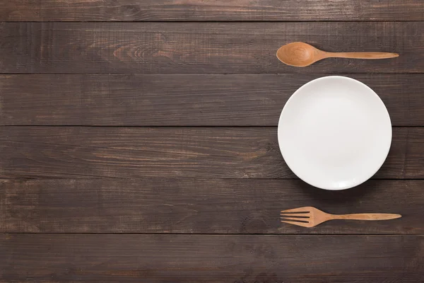 Concepto de comer. Cuchara, tenedor y plato blanco en el fondo de madera — Foto de Stock