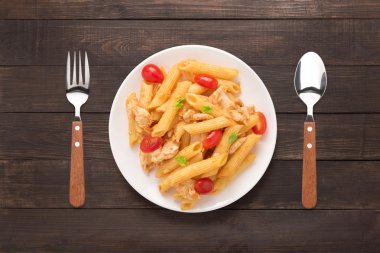 Ahşap arka plan üzerinde tavuk domates soslu Penne makarna