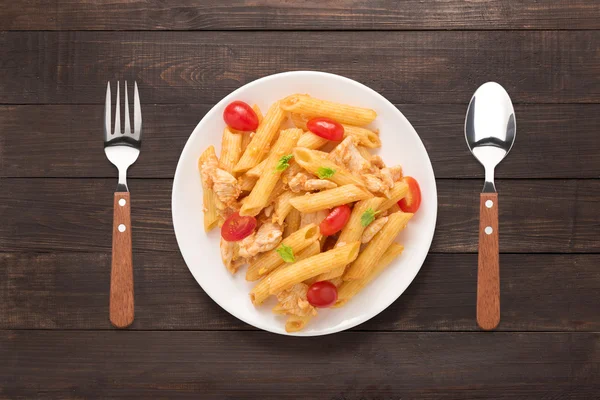 Ahşap arka plan üzerinde tavuk domates soslu Penne makarna