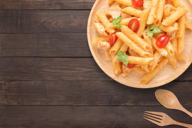 Ahşap arka plan üzerinde tavuk domates soslu Penne makarna.