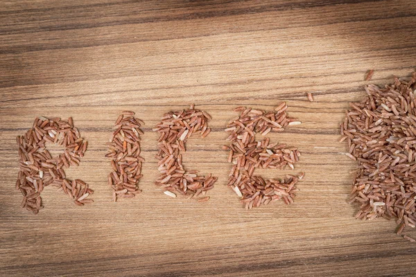 Hnědá rýže na dřevěné pozadí — Stock fotografie