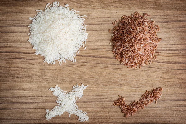 Hnědá rýže a rýže na dřevěné pozadí — Stock fotografie