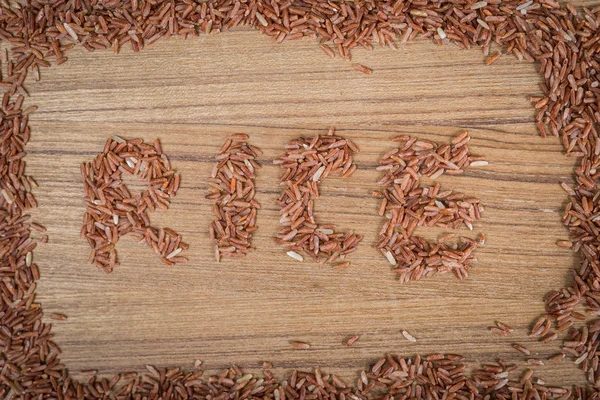 Brown rice on wooden background — Stock Photo, Image
