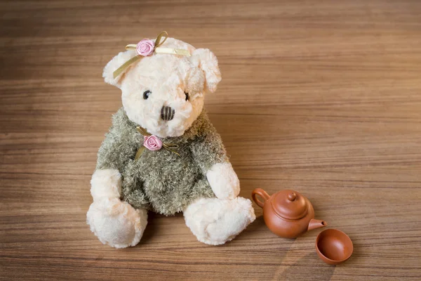 Brinquedo ursinho e chá chaleira e xícara no fundo de madeira — Fotografia de Stock