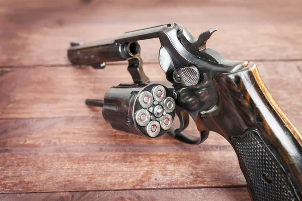 Pistola de revólver preto com balas isoladas em fundo de madeira — Fotografia de Stock