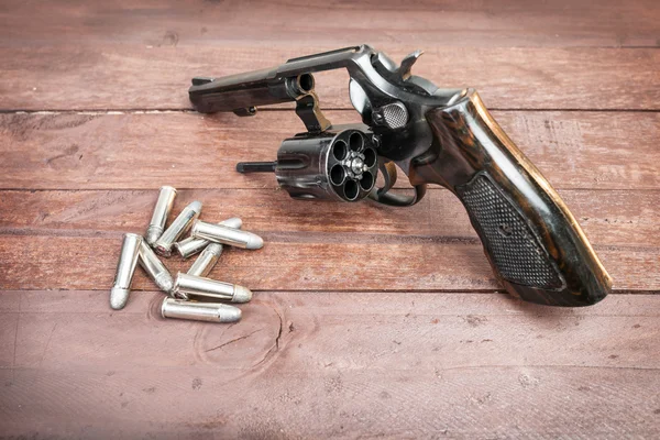 Černá revolver zbraň s odrážkami izolované dřevěné pozadí — Stock fotografie