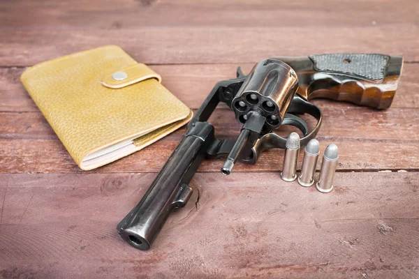 Fekete revolver, pisztoly és és fa háttér felett a bőr táska — Stock Fotó
