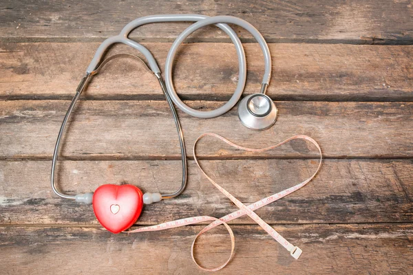 Red heart measuring with stethoscope and red pills isolated on w — Stock Photo, Image