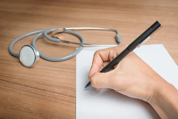 Hand with pen over blank paper form with stethoscope — Stock Photo, Image