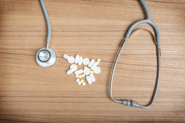 Medical concept with pills and stethoscope on table wooden — Stock Photo, Image