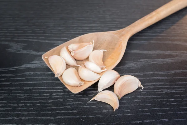 Garlic herb whole cloves in wooden spoons — Stock Photo, Image