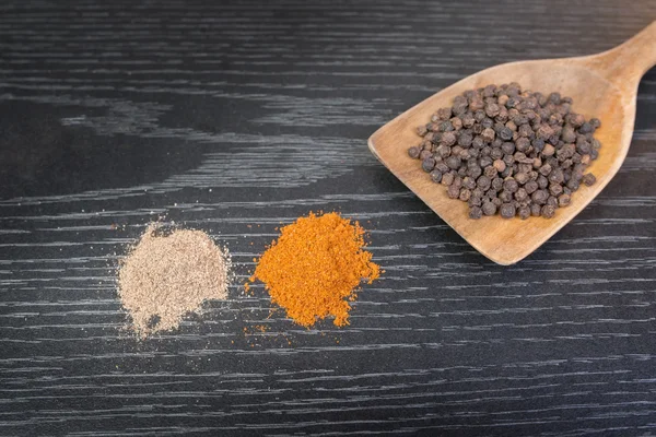 Assorted spices and condiments on table black wooden — Stock Photo, Image