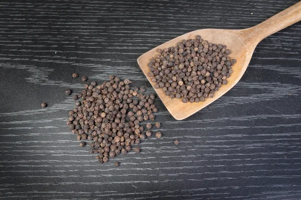 Peppercorns in a spoon on rustic wooden table — Stock Photo, Image