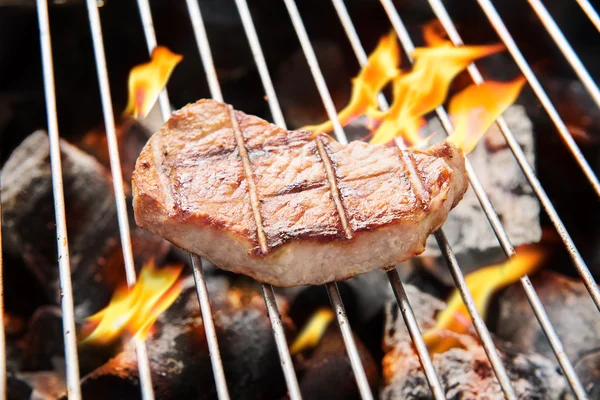 Pork steak cooking over flaming grill. — Stock Photo, Image