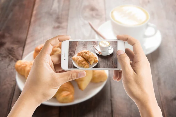 Taking photo of fresh baked croissants and coffee on wood table — Stock Photo, Image